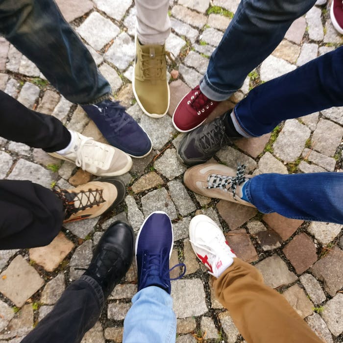 Home Circle of sneakers on cobblestone pavement representing diversity and urban fashion.